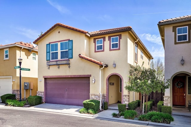 mediterranean / spanish-style home with concrete driveway, a tile roof, stucco siding, a garage, and stone siding