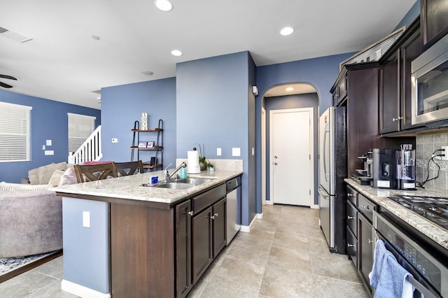 kitchen with visible vents, arched walkways, a sink, dark brown cabinets, and appliances with stainless steel finishes