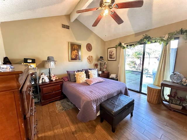 bedroom featuring visible vents, lofted ceiling with beams, a textured ceiling, wood finished floors, and access to exterior