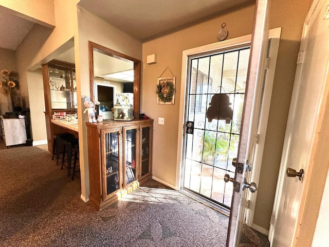 doorway to outside with baseboards and carpet floors