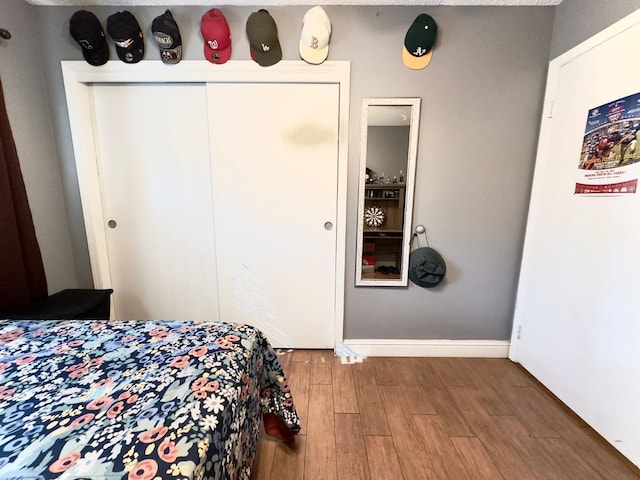 bedroom featuring wood finished floors, a closet, and baseboards