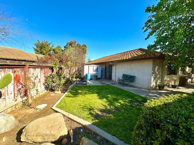 view of yard with a patio, an outbuilding, a fenced backyard, and a storage shed