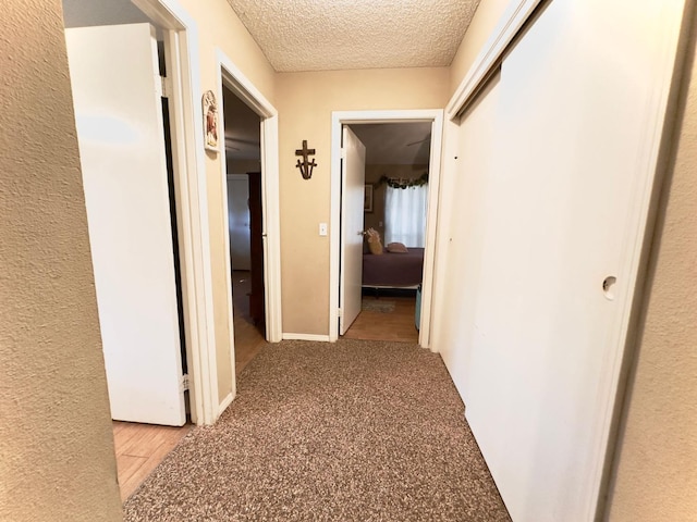 corridor featuring light carpet and a textured ceiling