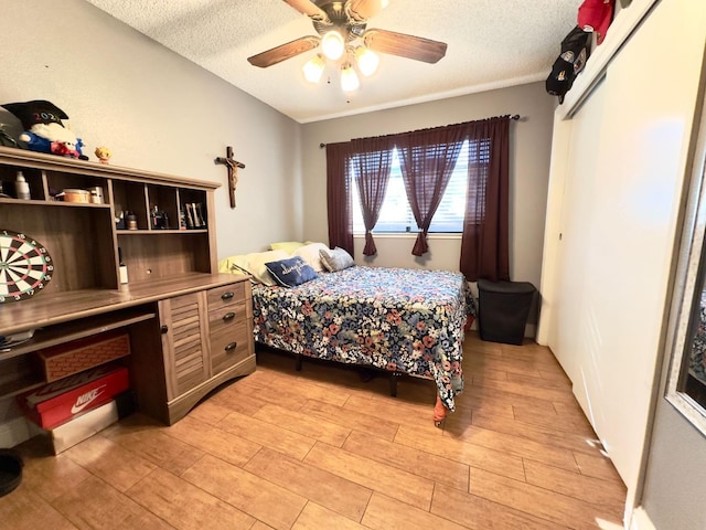 bedroom with a textured ceiling, light wood-type flooring, and ceiling fan