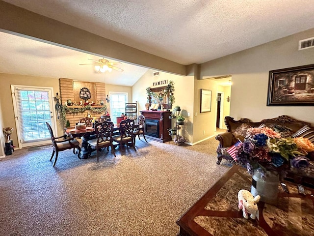 dining space with visible vents, carpet, vaulted ceiling, a glass covered fireplace, and a textured ceiling