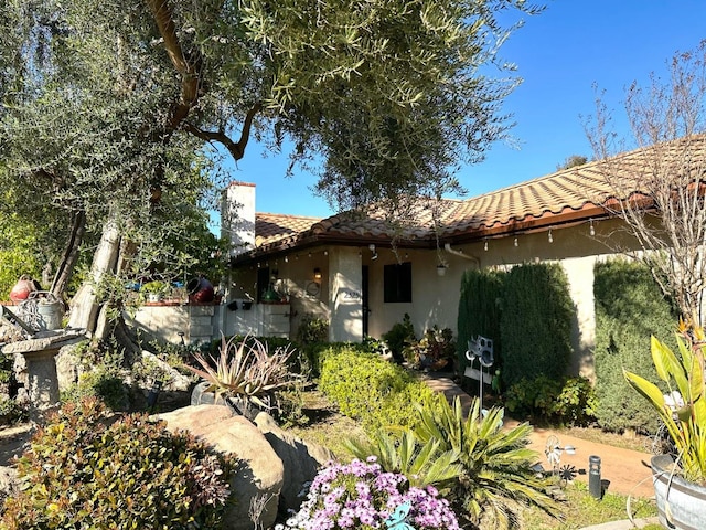 exterior space with stucco siding, a tiled roof, and a chimney