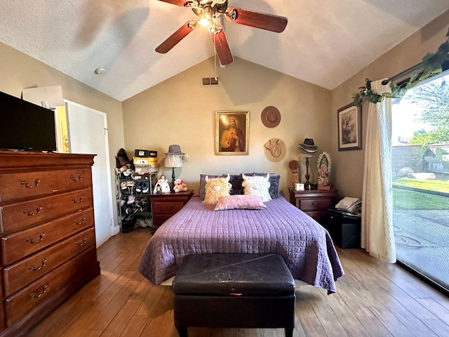 bedroom featuring access to exterior, visible vents, lofted ceiling with beams, hardwood / wood-style flooring, and a ceiling fan