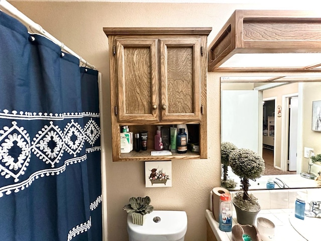 bathroom featuring a shower with curtain, toilet, and a textured wall