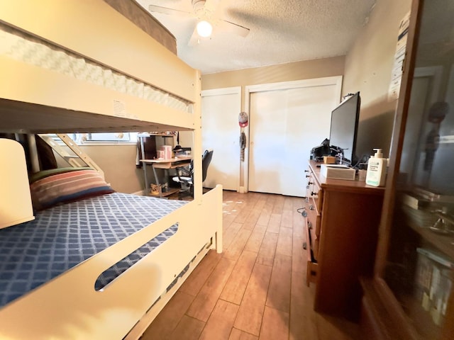 bedroom with ceiling fan, wood finished floors, multiple closets, and a textured ceiling