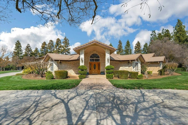 view of front of property with stone siding, a tiled roof, driveway, and a front lawn