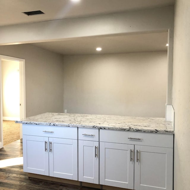 interior space with dark wood-style floors, visible vents, recessed lighting, and light stone countertops