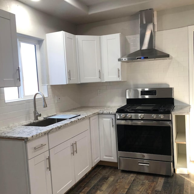 kitchen with a sink, white cabinets, wall chimney range hood, stainless steel range with gas stovetop, and dark wood-style flooring