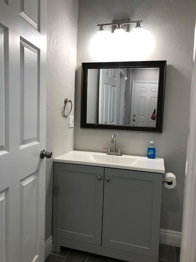 bathroom with tile patterned flooring, baseboards, vanity, and a textured wall