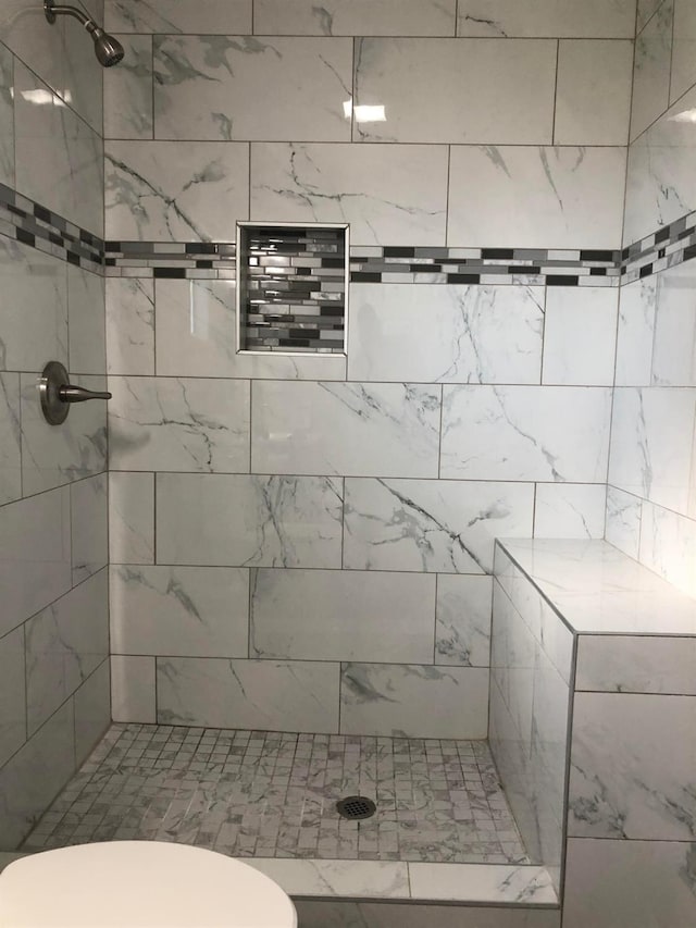 full bath with tiled shower and toilet