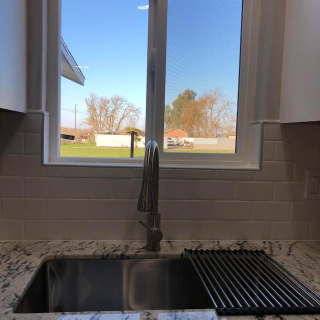 room details with light stone counters, tasteful backsplash, and a sink