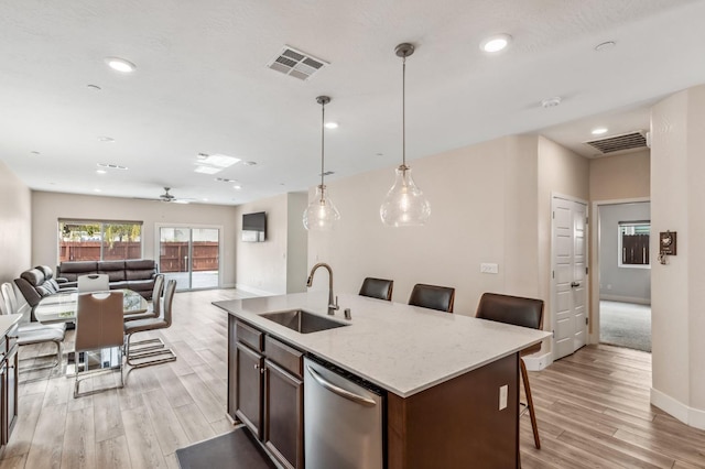 kitchen featuring visible vents, light wood-style flooring, a sink, stainless steel dishwasher, and open floor plan