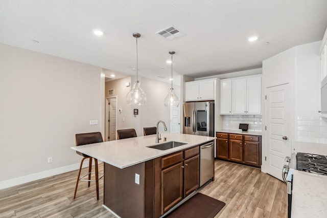 kitchen featuring tasteful backsplash, visible vents, a kitchen bar, appliances with stainless steel finishes, and a sink