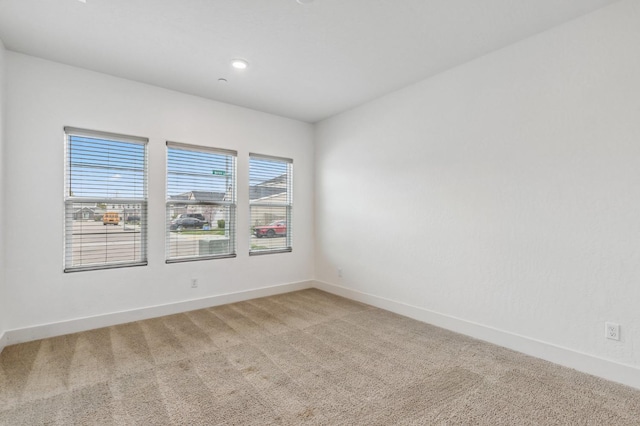 unfurnished room featuring light colored carpet and baseboards