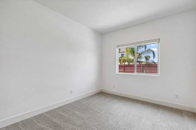 carpeted spare room featuring baseboards