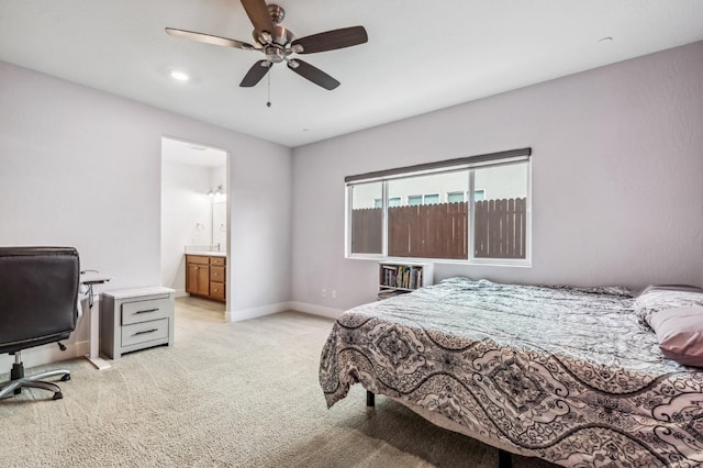 bedroom with baseboards, light colored carpet, ensuite bath, and a ceiling fan