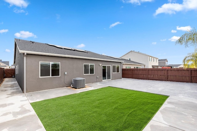 rear view of property with solar panels, stucco siding, a lawn, a fenced backyard, and a patio area