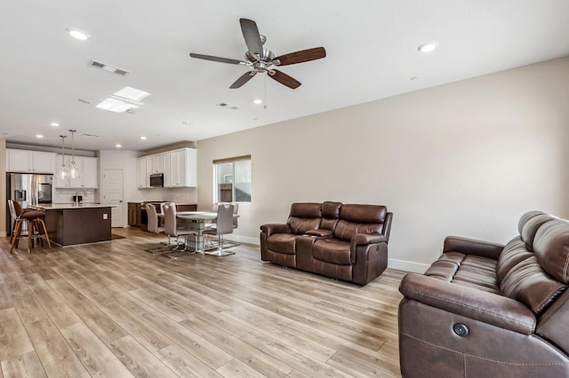 living room with recessed lighting, visible vents, baseboards, and light wood-style flooring