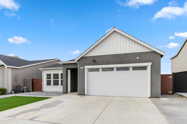 view of front of home featuring stucco siding, driveway, fence, board and batten siding, and a garage