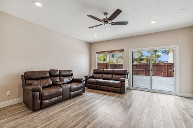 living area with a wealth of natural light, light wood-type flooring, and baseboards