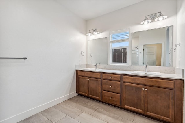 full bathroom featuring tile patterned flooring, double vanity, baseboards, and a sink