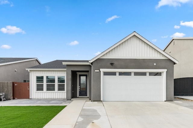 view of front facade with board and batten siding, an attached garage, and fence