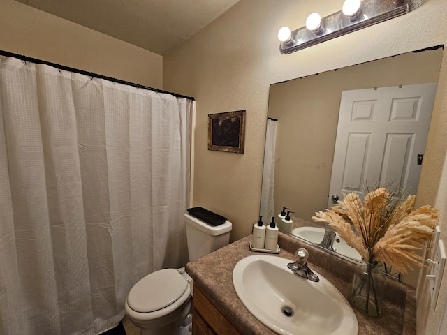 bathroom with toilet, vanity, and a textured wall