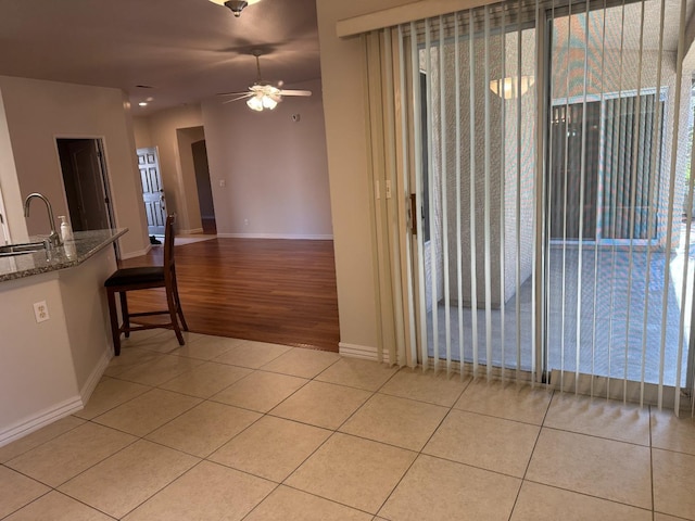 interior space featuring light tile patterned flooring, baseboards, and a sink