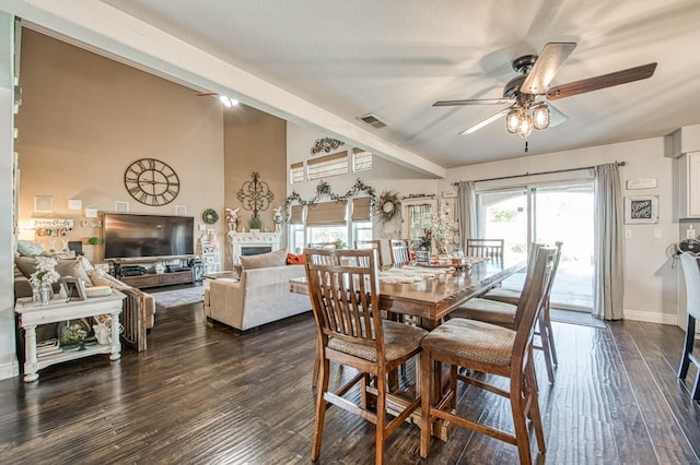 dining area featuring visible vents, dark wood-type flooring, baseboards, lofted ceiling, and a glass covered fireplace