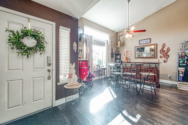 dining area featuring a ceiling fan, wood finished floors, baseboards, lofted ceiling, and a dry bar