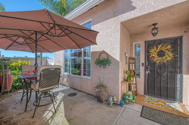 doorway to property featuring a patio area, fence, and stucco siding