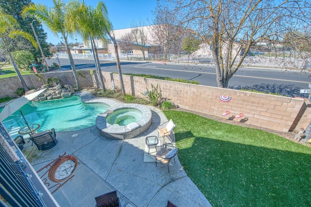 view of swimming pool with a fenced backyard, a lawn, and a pool with connected hot tub