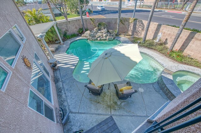 view of pool featuring a patio, a fenced backyard, and a pool with connected hot tub