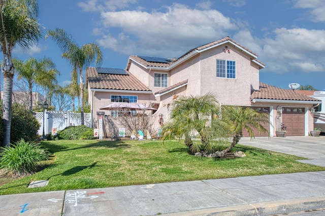 mediterranean / spanish home featuring stucco siding, driveway, a front yard, and fence