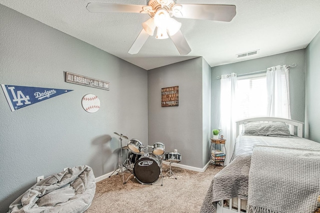 carpeted bedroom with visible vents, a ceiling fan, a textured ceiling, baseboards, and a textured wall