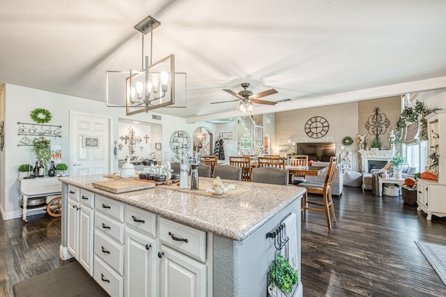 kitchen featuring a kitchen island, open floor plan, dark wood finished floors, a fireplace, and hanging light fixtures