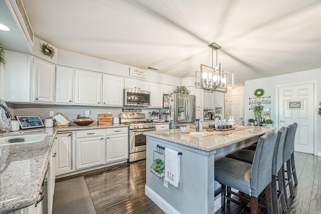 kitchen with a sink, a kitchen breakfast bar, dark wood finished floors, and stainless steel appliances