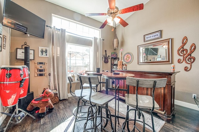 dining area with a ceiling fan, a dry bar, wood finished floors, and baseboards