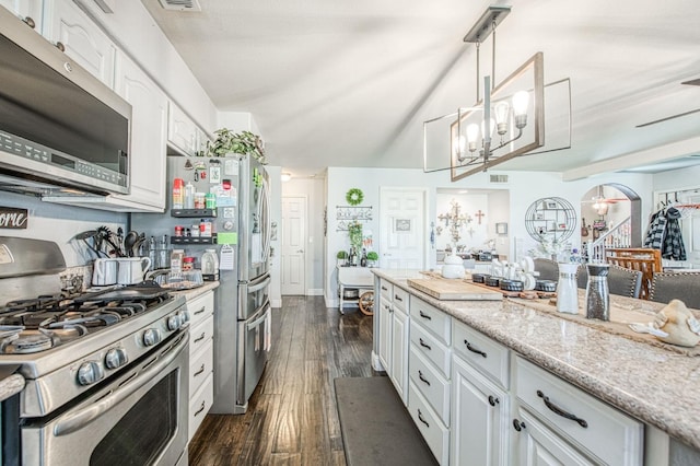 kitchen featuring dark wood-style floors, light stone countertops, arched walkways, stainless steel appliances, and white cabinets