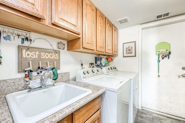 washroom with a sink, visible vents, cabinet space, and independent washer and dryer