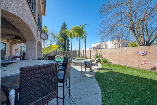 view of patio with an in ground hot tub, a ceiling fan, and a fenced backyard