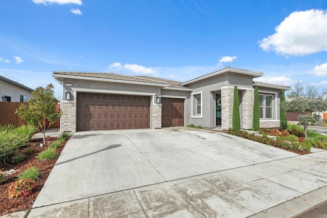 prairie-style home featuring stucco siding, stone siding, an attached garage, and fence