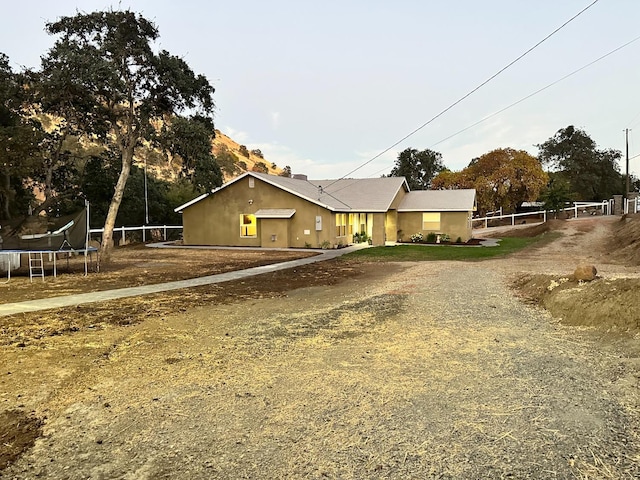 view of front facade with a trampoline, gravel driveway, and fence