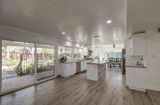 kitchen with backsplash, appliances with stainless steel finishes, white cabinets, and a center island