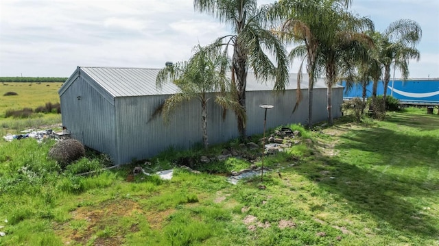 exterior space with a lawn, metal roof, an outdoor structure, and a pole building