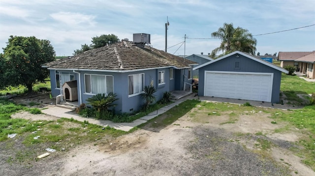 view of front of property featuring an outbuilding, stucco siding, a garage, and dirt driveway